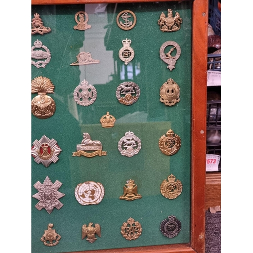 1703 - A framed display of British military cap badges. (54)