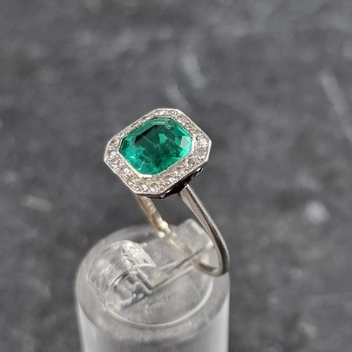 329 - An emerald and diamond cluster ring, the central trap cut emerald of approximately 1.4ct, surrounded... 