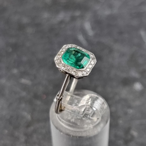 329 - An emerald and diamond cluster ring, the central trap cut emerald of approximately 1.4ct, surrounded... 