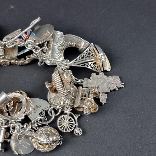 435 - A charm bracelet, with padlock clasp set with approximately 40 charms and similar, mostly stamped si... 