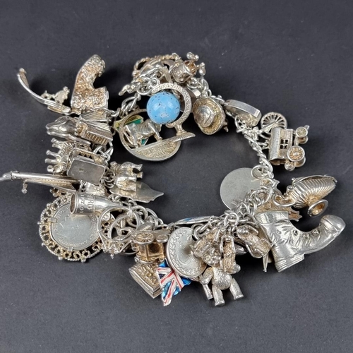 435 - A charm bracelet, with padlock clasp set with approximately 40 charms and similar, mostly stamped si... 