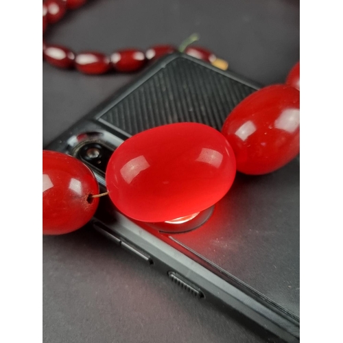 480 - A vintage cherry amber style Bakelite necklace, having forty four beads, graduated from 33mm to 13mm... 