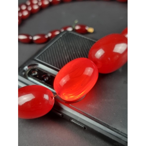 480 - A vintage cherry amber style Bakelite necklace, having forty four beads, graduated from 33mm to 13mm... 