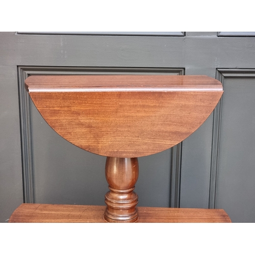 1028 - A George IV mahogany three-tier drop leaf dumb waiter, 123cm high.