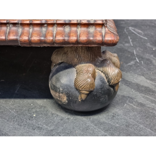 1058 - A Victorian carved rosewood and button upholstered ottoman, on gilt and ebonized ball & claw fee... 