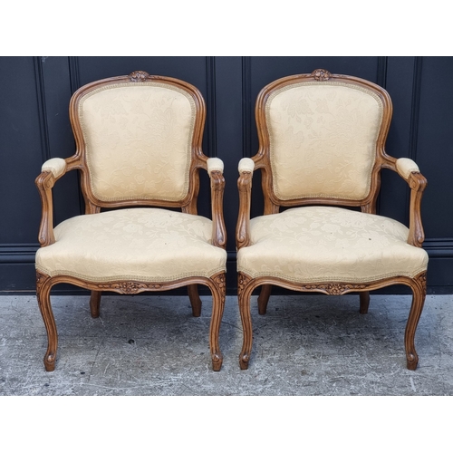 1061 - A pair of Louis XV style carved walnut fauteuils.