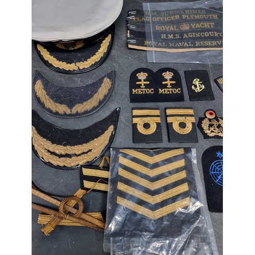 27 - A group of Royal Navy insignia and hat tallies, including royal yacht, HMS Agincourt and HM Submarin... 