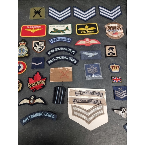 28 - A collection of RAF items, comprising: insignia, patches, wings, an officers peaked cap, and a sword... 