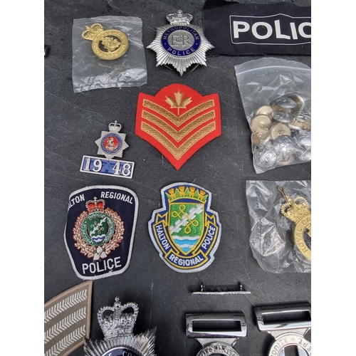 31 - A large collection of British and Colonial Police items; to include cap badges; handcuffs; and belt ... 