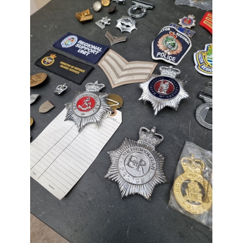 31 - A large collection of British and Colonial Police items; to include cap badges; handcuffs; and belt ... 