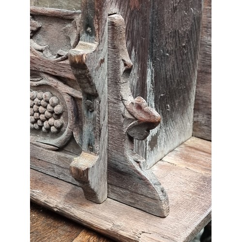 1007 - A 17th century carved oak boarded stool, the frieze carved with fruiting vines and tracery, 53cm wid... 