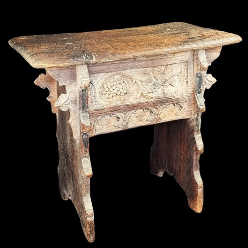 1007 - A 17th century carved oak boarded stool, the frieze carved with fruiting vines and tracery, 53cm wid... 