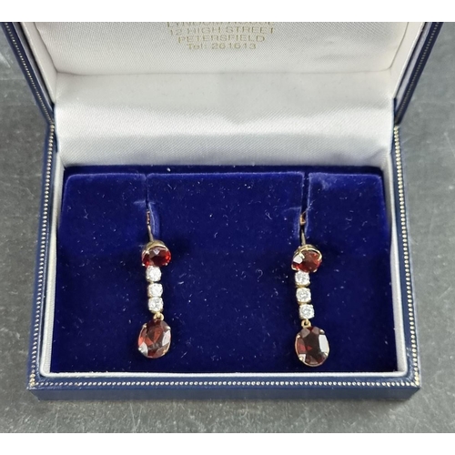 166 - A pair of yellow metal garnet and white gemstone set pendant earrings, 29mm long, in Trevor Towner b... 