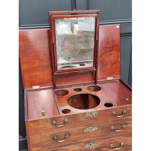 1034 - An unusual George III mahogany and boxwood strung dressing chest, the hinged top enclosing a fitted ... 