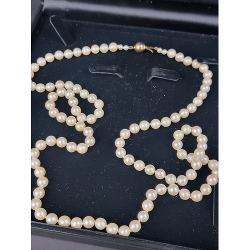 158 - A cultured pearl necklace, having clasp stamped '750', 80cm long; together with another synthetic pe... 