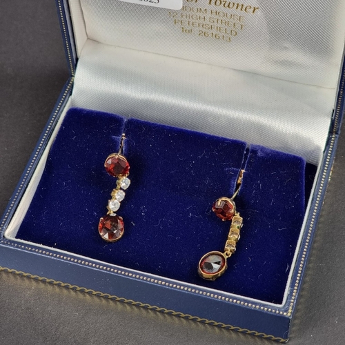 166 - A pair of yellow metal garnet and white gemstone set pendant earrings, 29mm long, in Trevor Towner b... 