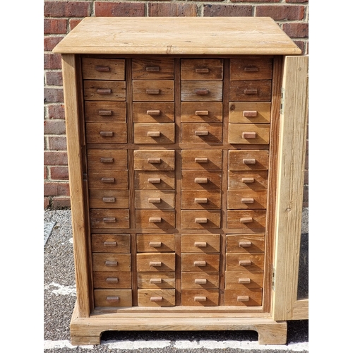 1010A - An interesting pine multi-drawer cabinet, the glazed panel door enclosing forty eight small drawers,... 