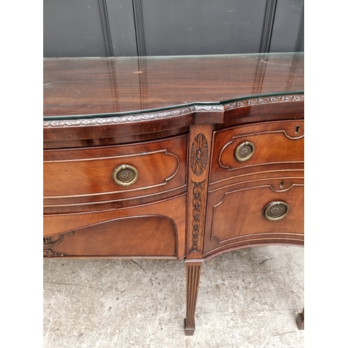1046 - A late George III carved mahogany serpentine fronted sideboard, 182cm wide.