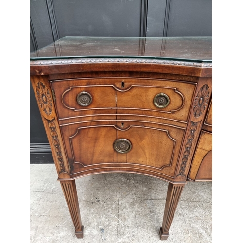 1046 - A late George III carved mahogany serpentine fronted sideboard, 182cm wide.