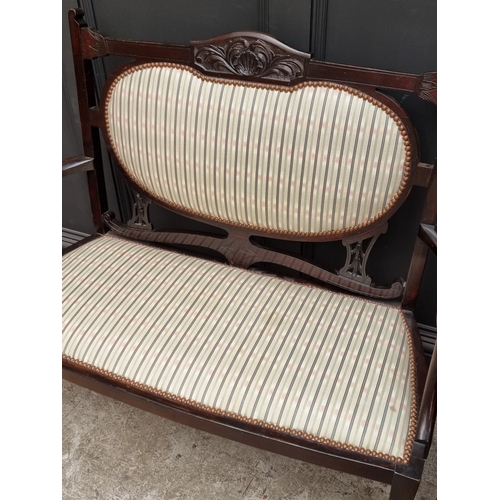 1059 - An Edwardian carved mahogany and upholstered three-piece salon suite, the settee 110.5cm wide.... 