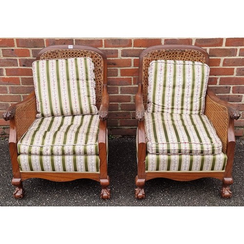 1069 - A pair of 1930s walnut and cane bergere chairs, with cushions.