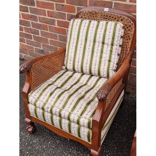 1069 - A pair of 1930s walnut and cane bergere chairs, with cushions.