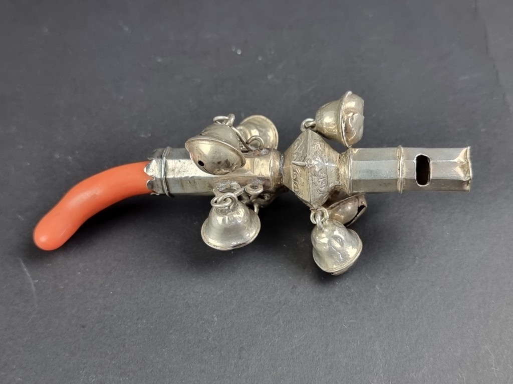 A coral handled silver rattle, marks rubbed, 11.5cm long, (s.d.).
