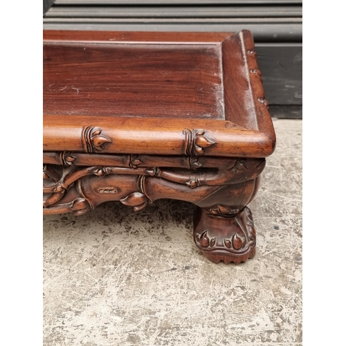 1023 - A Chinese carved hardwood low stand or table, 97cm wide.