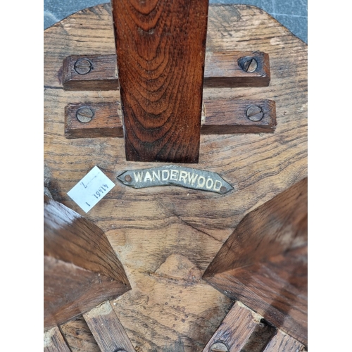 1050 - A rustic elm tripod milking stool, labelled 'Wanderwood', 29.5cm wide.