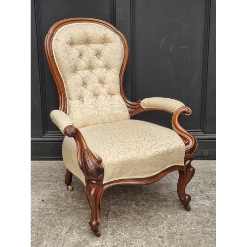 1062 - A Victorian carved walnut and button upholstered open arm occasional chair.