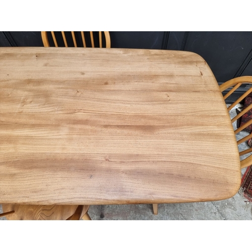 1073 - A mid-century Ercol blonde dining suite, comprising: a Windsor table, 152cm long; and a set of six '... 