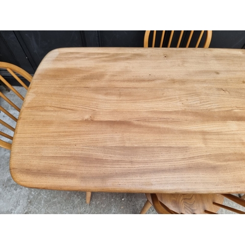 1073 - A mid-century Ercol blonde dining suite, comprising: a Windsor table, 152cm long; and a set of six '... 