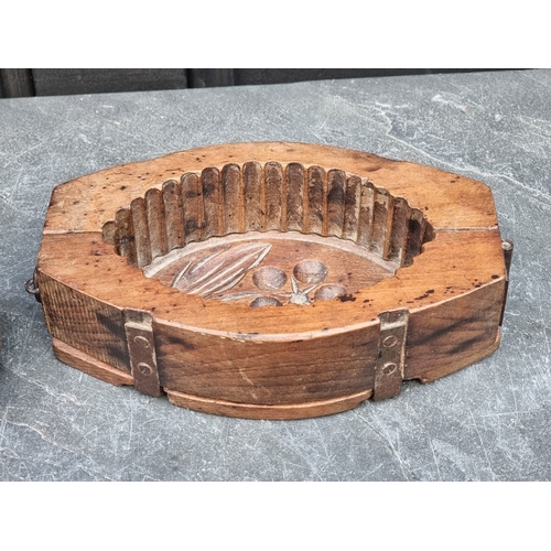 1416 - A vintage treen butter mould, 21.5cm wide; together with a spindle whorl, 7cm high. (2)... 