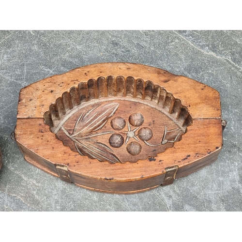 1416 - A vintage treen butter mould, 21.5cm wide; together with a spindle whorl, 7cm high. (2)... 