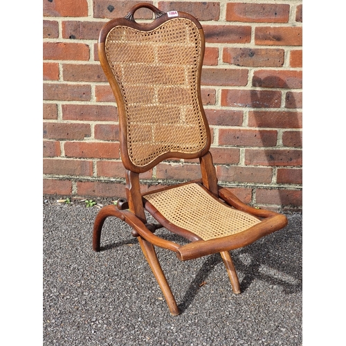 1064 - A small Victorian walnut and cane folding chair.