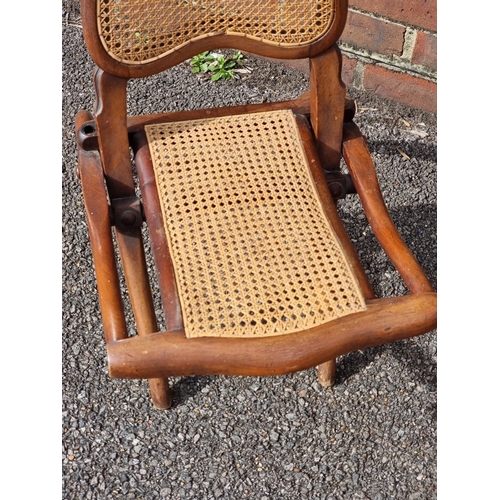 1064 - A small Victorian walnut and cane folding chair.