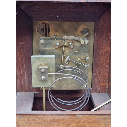 1184 - A late 19th century carved oak mantel clock, 44cm high, with pendulum.