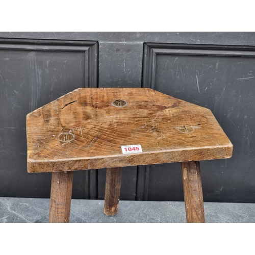 1045 - An antique ash and elm tripod milking stool, 33cm wide.