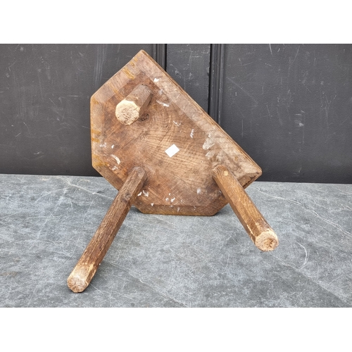 1045 - An antique ash and elm tripod milking stool, 33cm wide.