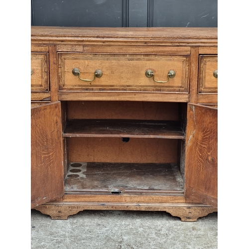 1051 - A George III oak, walnut crossbanded and line inlaid dresser base, 187cm wide.