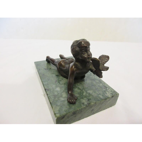 131 - A bronze figure of a young boy holding a bird and raised on a green marble base.