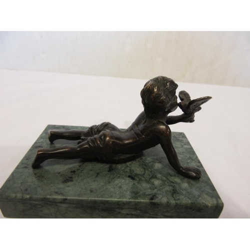 131 - A bronze figure of a young boy holding a bird and raised on a green marble base.