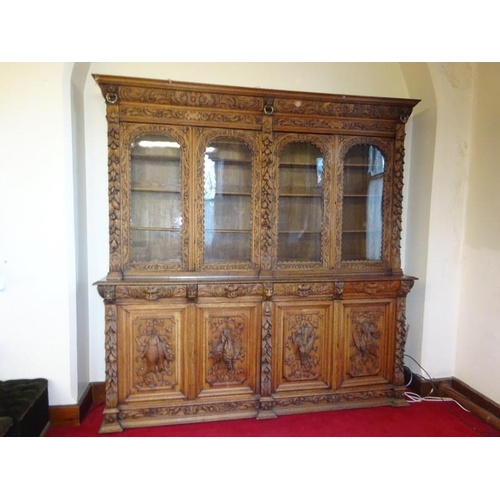 150 - A large antique carved oak bookcase, the upper section having carved freize with lion mask decoratio... 