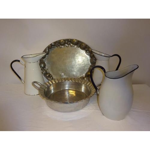 30 - A pewter dish and oval platter together with three enamel jugs. (5)