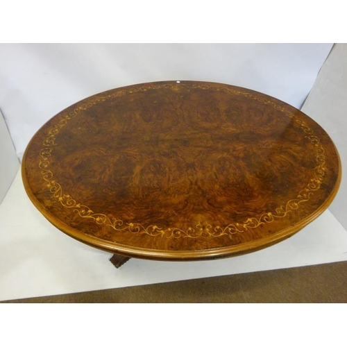 77 - A Victorian inlaid and figured walnut drawing room table, the oval top on centre pod support having ... 