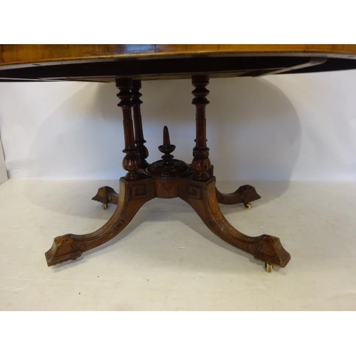 77 - A Victorian inlaid and figured walnut drawing room table, the oval top on centre pod support having ... 