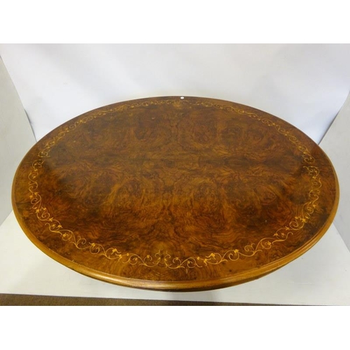 77 - A Victorian inlaid and figured walnut drawing room table, the oval top on centre pod support having ... 