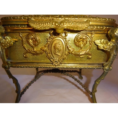 91 - A gilt metal jewellery box raised on four scroll legs.