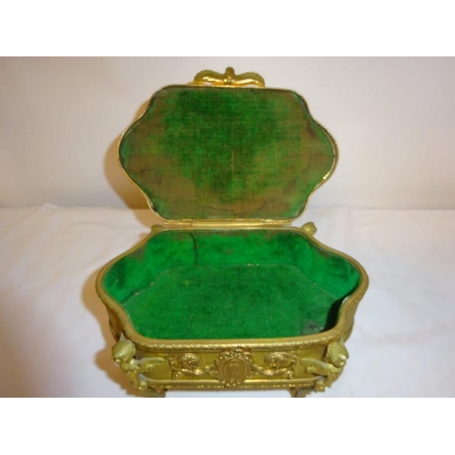 91 - A gilt metal jewellery box raised on four scroll legs.