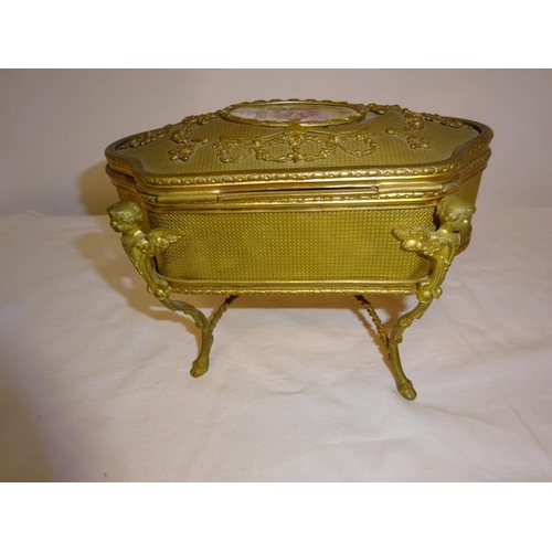 91 - A gilt metal jewellery box raised on four scroll legs.